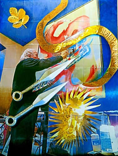 In einem surrealen Gemälde kreiert ein Künstler inmitten übergroßer goldener Scheren und eines Sonnenstrahlen-Designs, in dessen Nähe sich eine goldene, schlangenartige Gestalt windet. Darüber schwebt ein einzelnes Blatt, während leuchtende Blau-, Rot- und Gelbtöne miteinander tanzen. Die Szene deutet subtil auf das Chaos der Verschwörungstheorien hin, das hinter der Kreativität lauert.